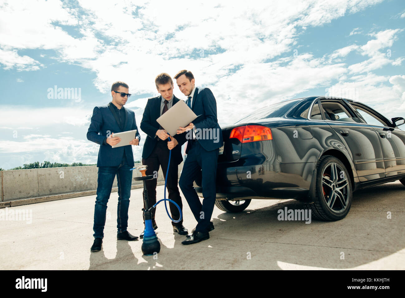 Trois businessman using digital tablet à l'extérieur contre voiture Banque D'Images