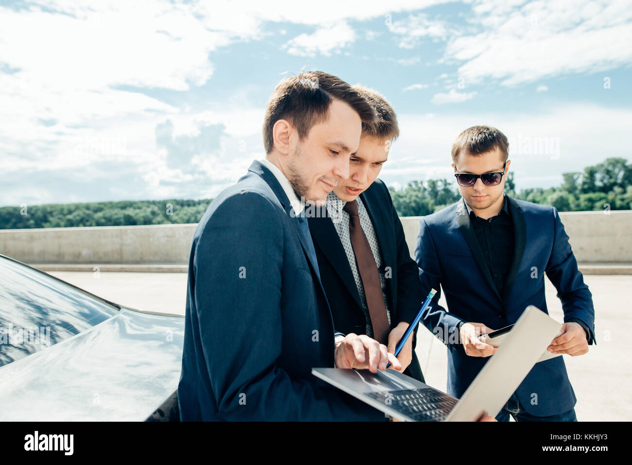 Trois businessman using digital tablet à l'extérieur contre voiture Banque D'Images