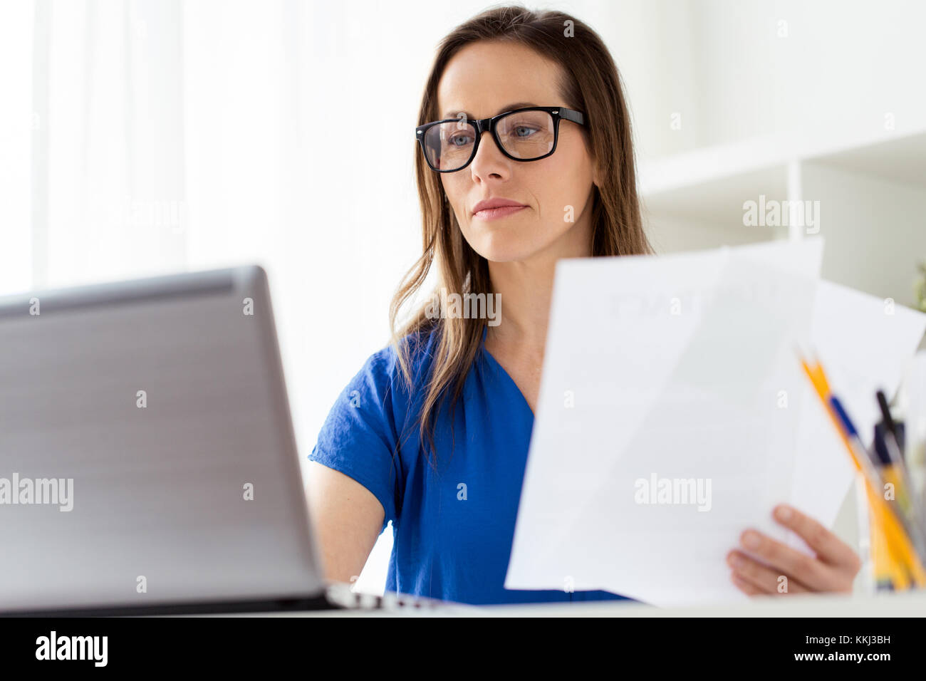 Businesswoman avec papiers et laptop at office Banque D'Images