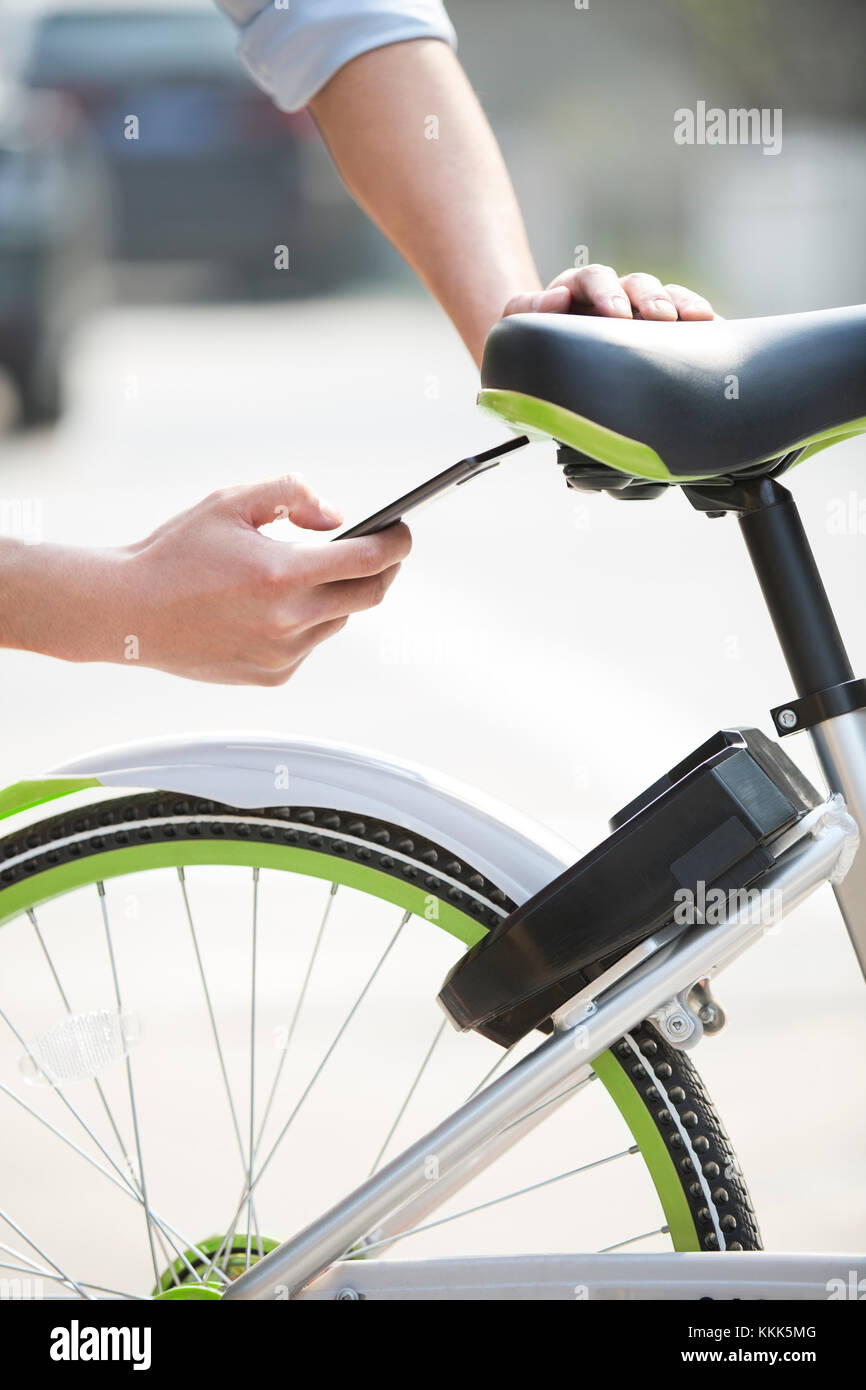 Les jeunes Chinois de la numérisation d'un QR code pour débloquer un vélo partager Banque D'Images