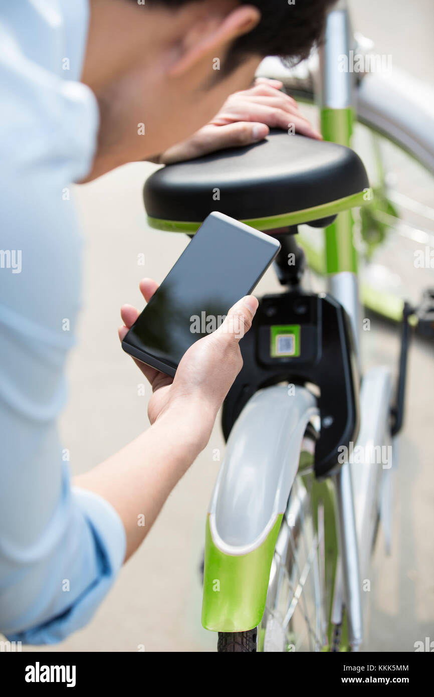 Les jeunes Chinois de la numérisation d'un QR code pour débloquer un vélo partager Banque D'Images