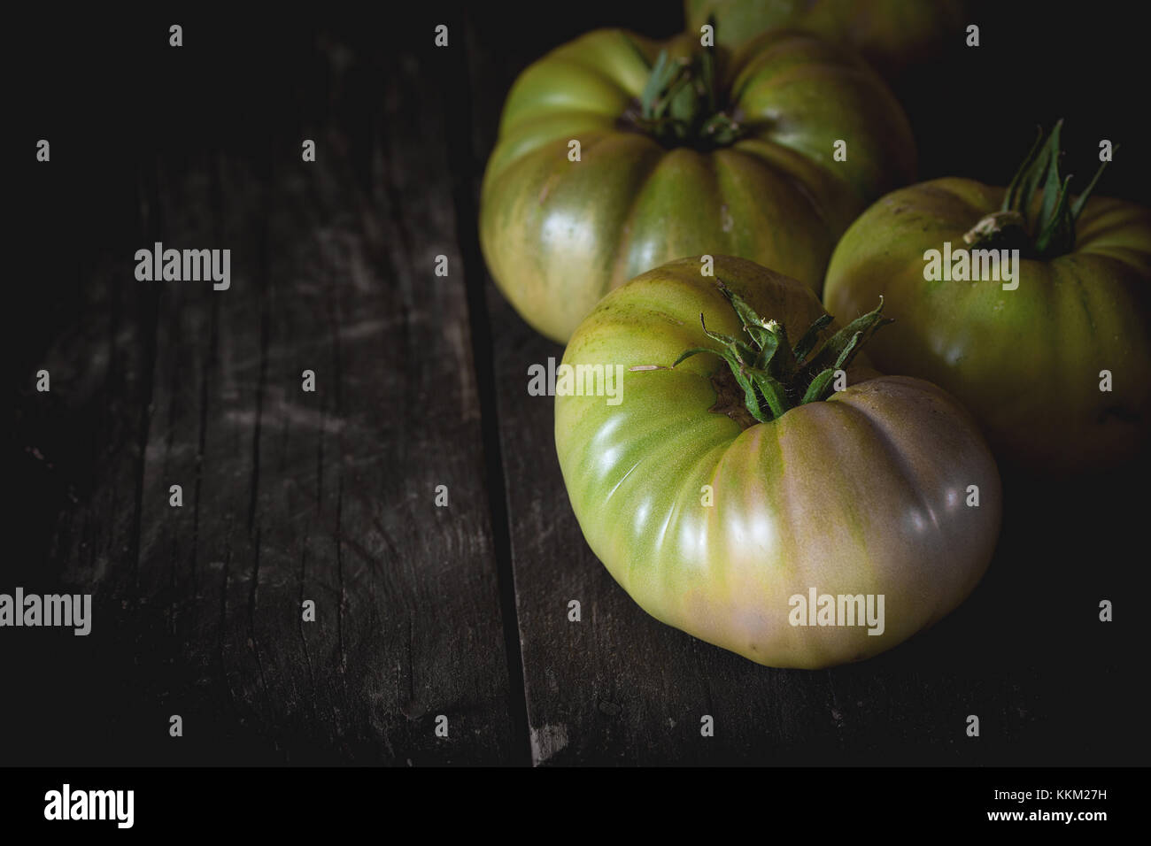 Gros fruit vert vert tomates raf plus vieille table en bois sombre de style rustique.. la lumière naturelle du jour. avec copie espace à gauche Banque D'Images