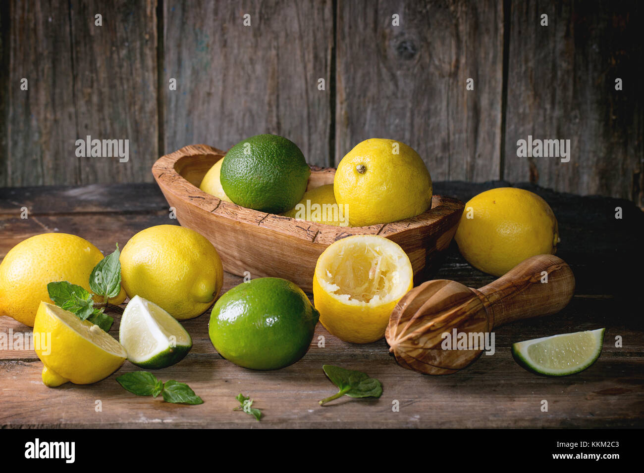 Tas d'ensemble et les tranches de citrons et limes bol en bois d'agrumes et de l'aléseur fond de bois Banque D'Images