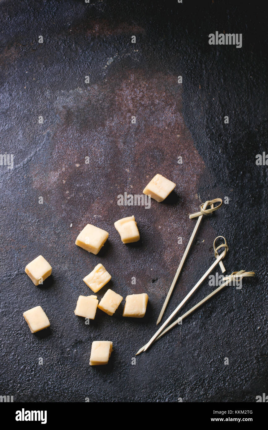 Petits cubes de fromage belge avec des bâtons à cocktail sur fond noir. vue d'en haut. Banque D'Images