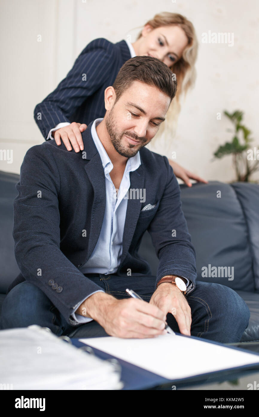 Jeune femme blonde rusé séducteur riche homme d'affaires à signer des documents, les gestionnaires de l'escroc Banque D'Images