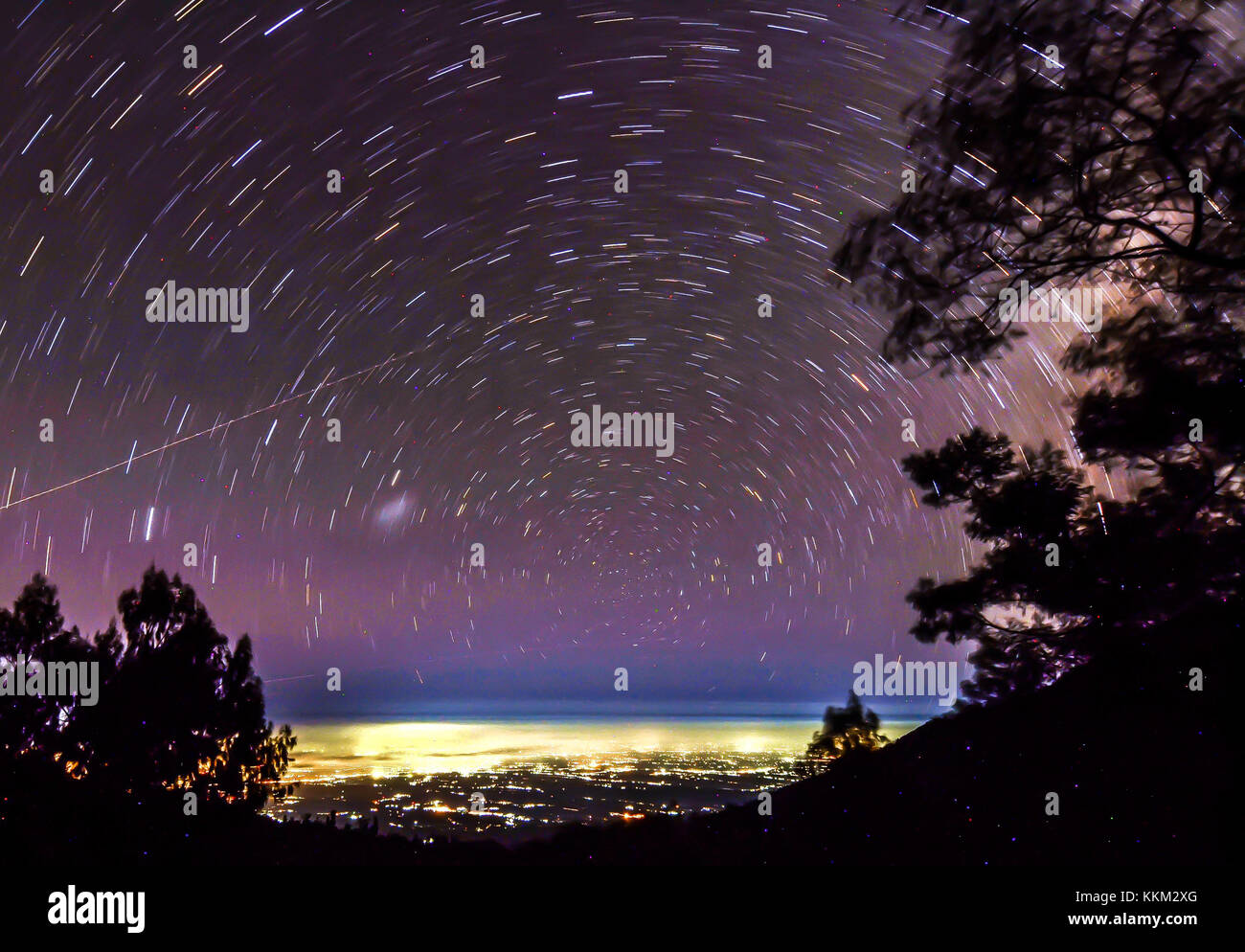 Star trail in kawah ijen avec la ville de banyuwangi en arrière-plan. Banque D'Images