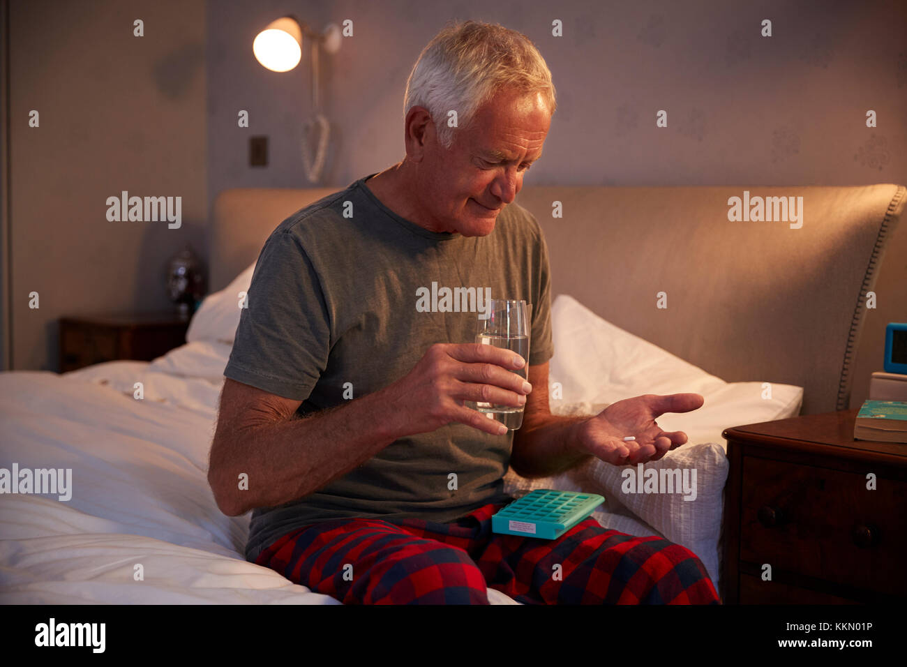 Senior Man Sitting on Bed At Home Prendre des médicaments Banque D'Images