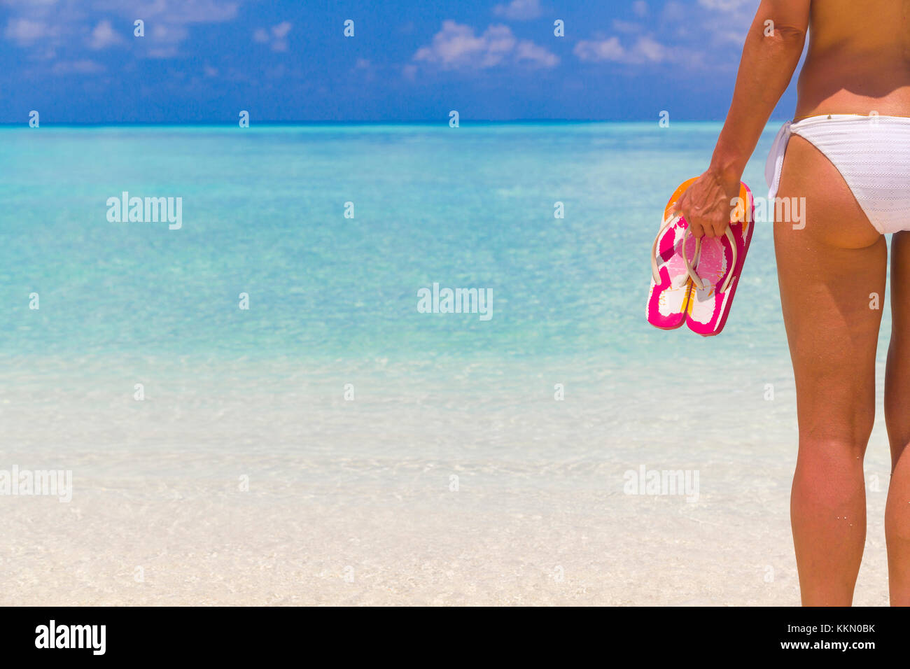 Woman holding tongs en étant debout sur la plage. Banque D'Images