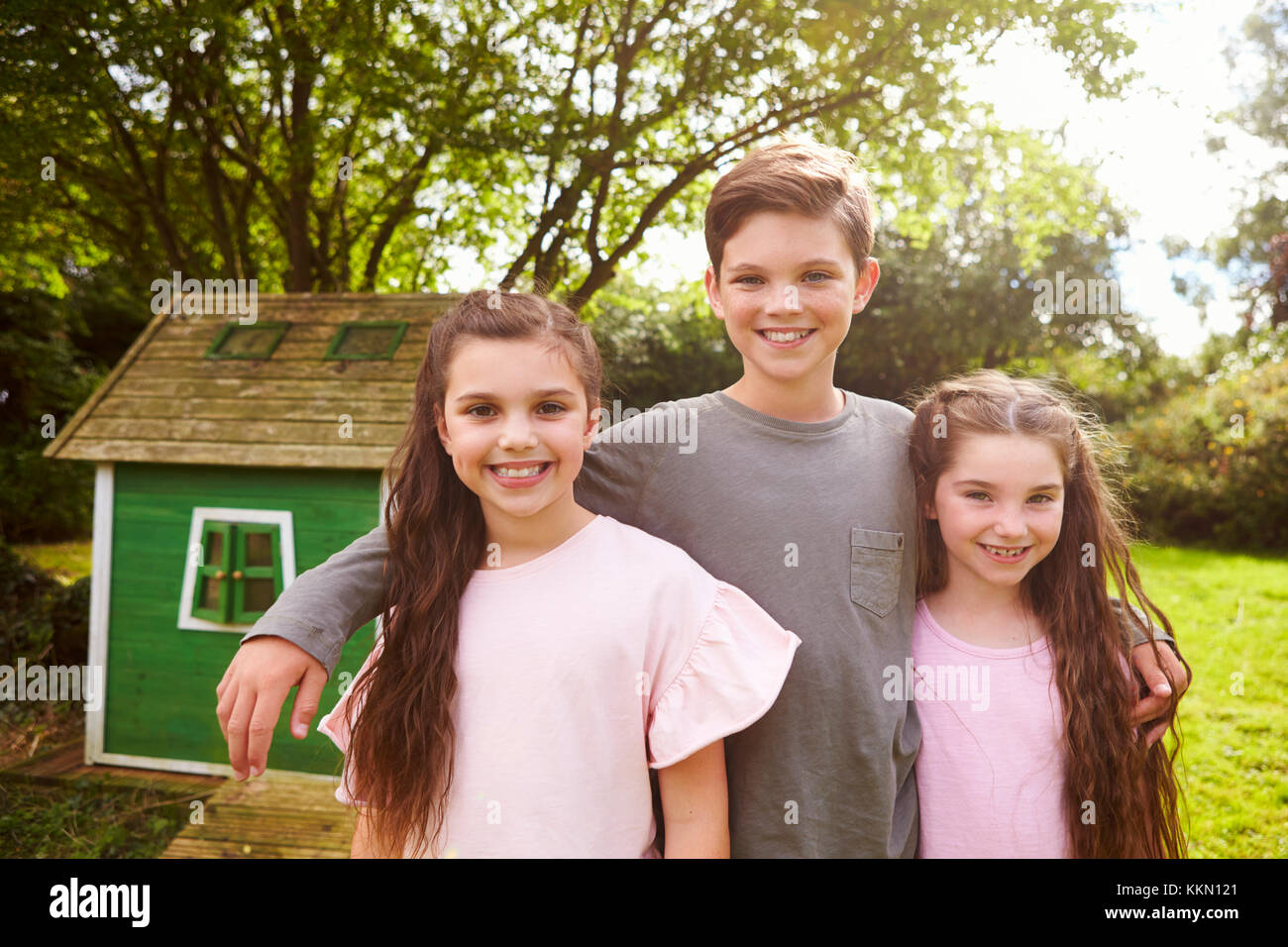 Portrait d'enfants debout dans jardin près de Playhouse Banque D'Images