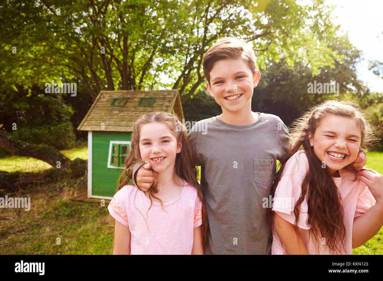Portrait d'enfants debout dans jardin près de Playhouse Banque D'Images