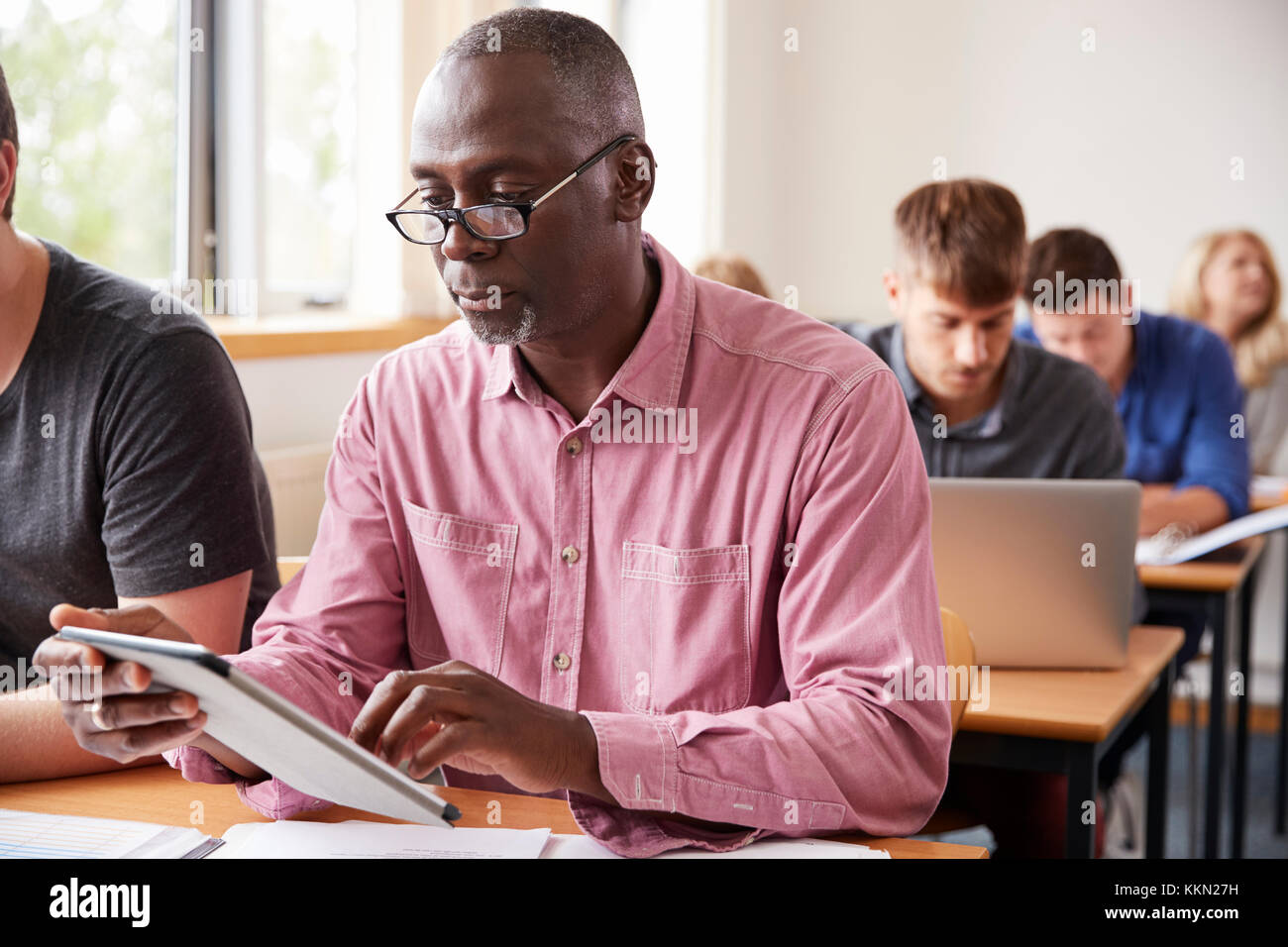Mature Student Using Digital Tablet In Cours pour Adultes Banque D'Images