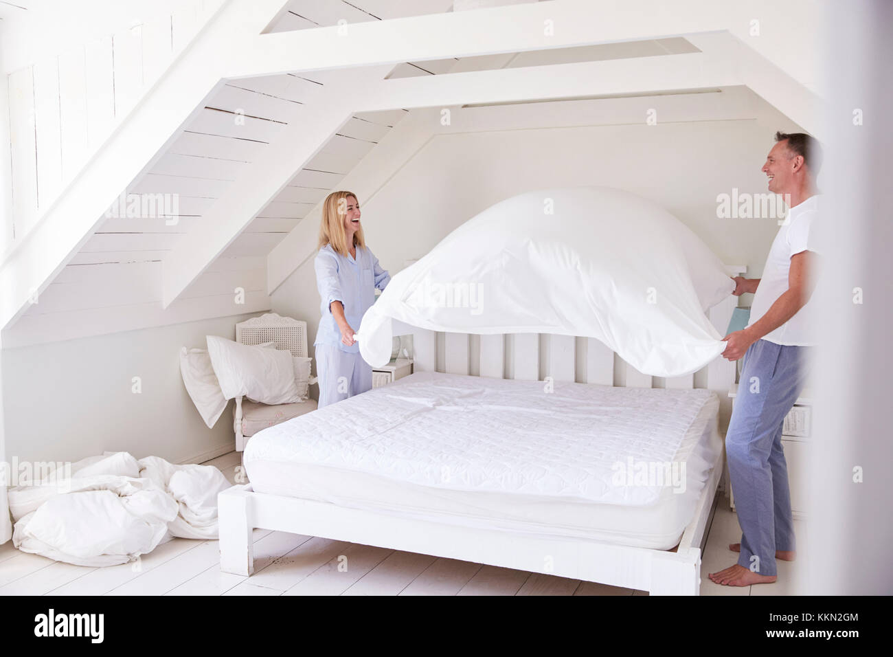 Couple Wearing Pyjamas faisant lit dans la matin Banque D'Images