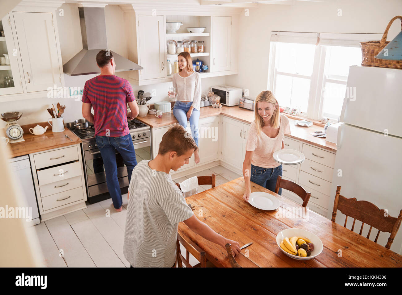 Famille avec adolescents portant la Table de repas en cuisine Banque D'Images