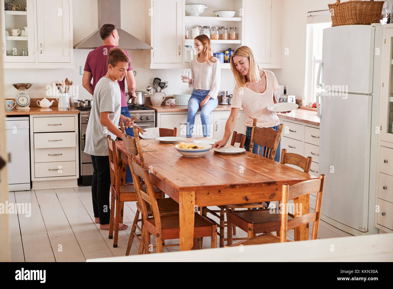 Famille avec adolescents portant la Table de repas en cuisine Banque D'Images