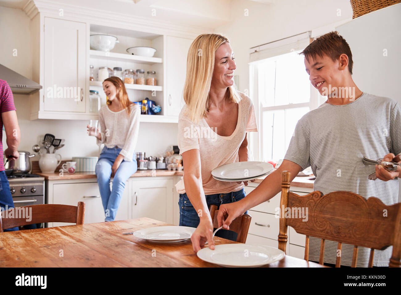 Famille avec adolescents portant la Table de repas en cuisine Banque D'Images