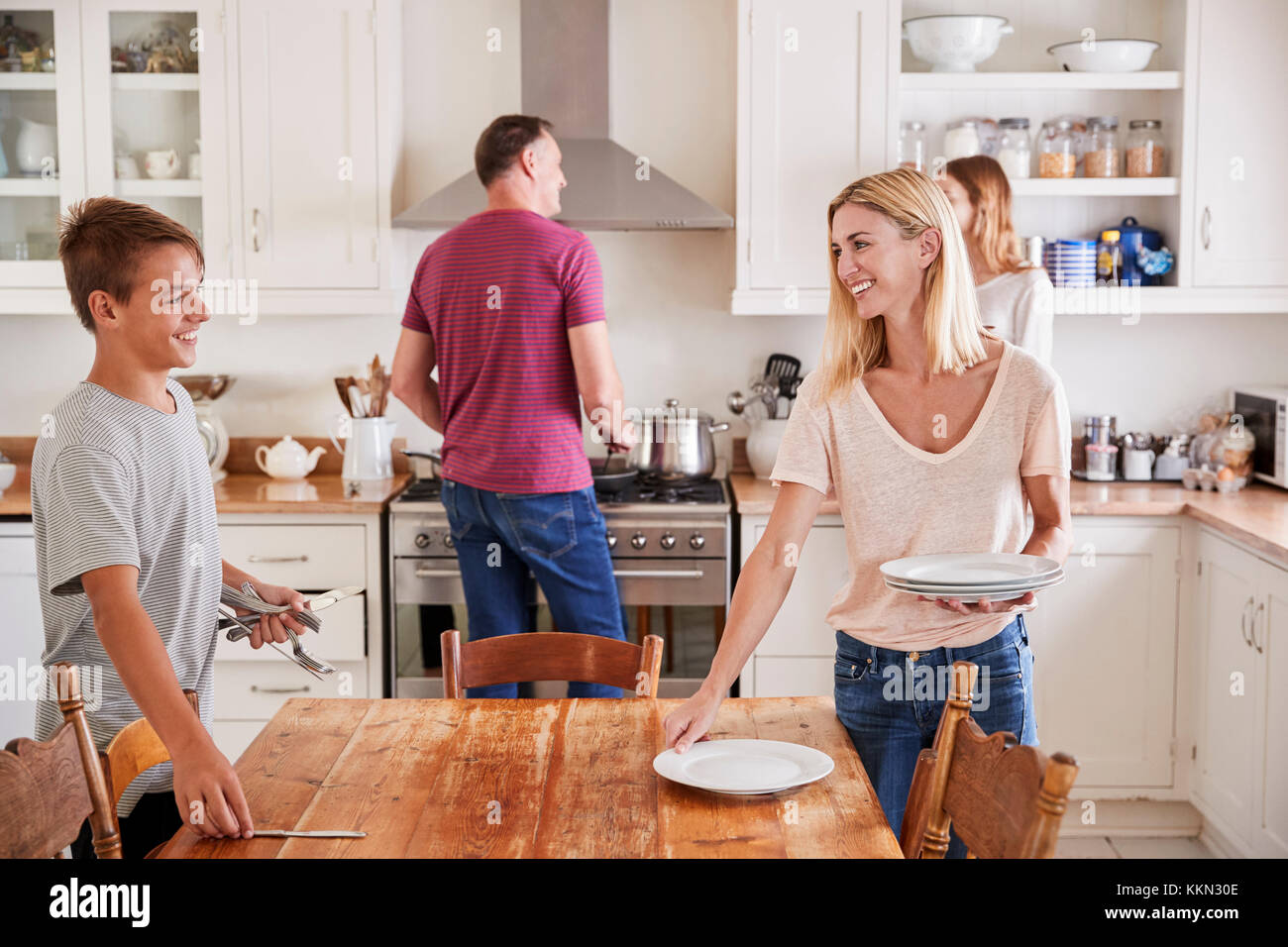 Famille avec adolescents portant la Table de repas en cuisine Banque D'Images