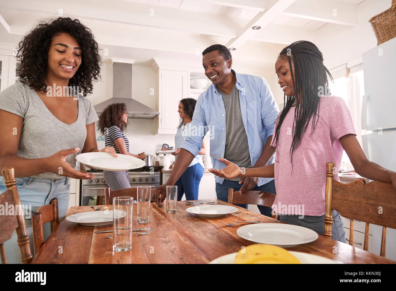 Famille avec filles adolescentes portant la Table de repas en cuisine Banque D'Images