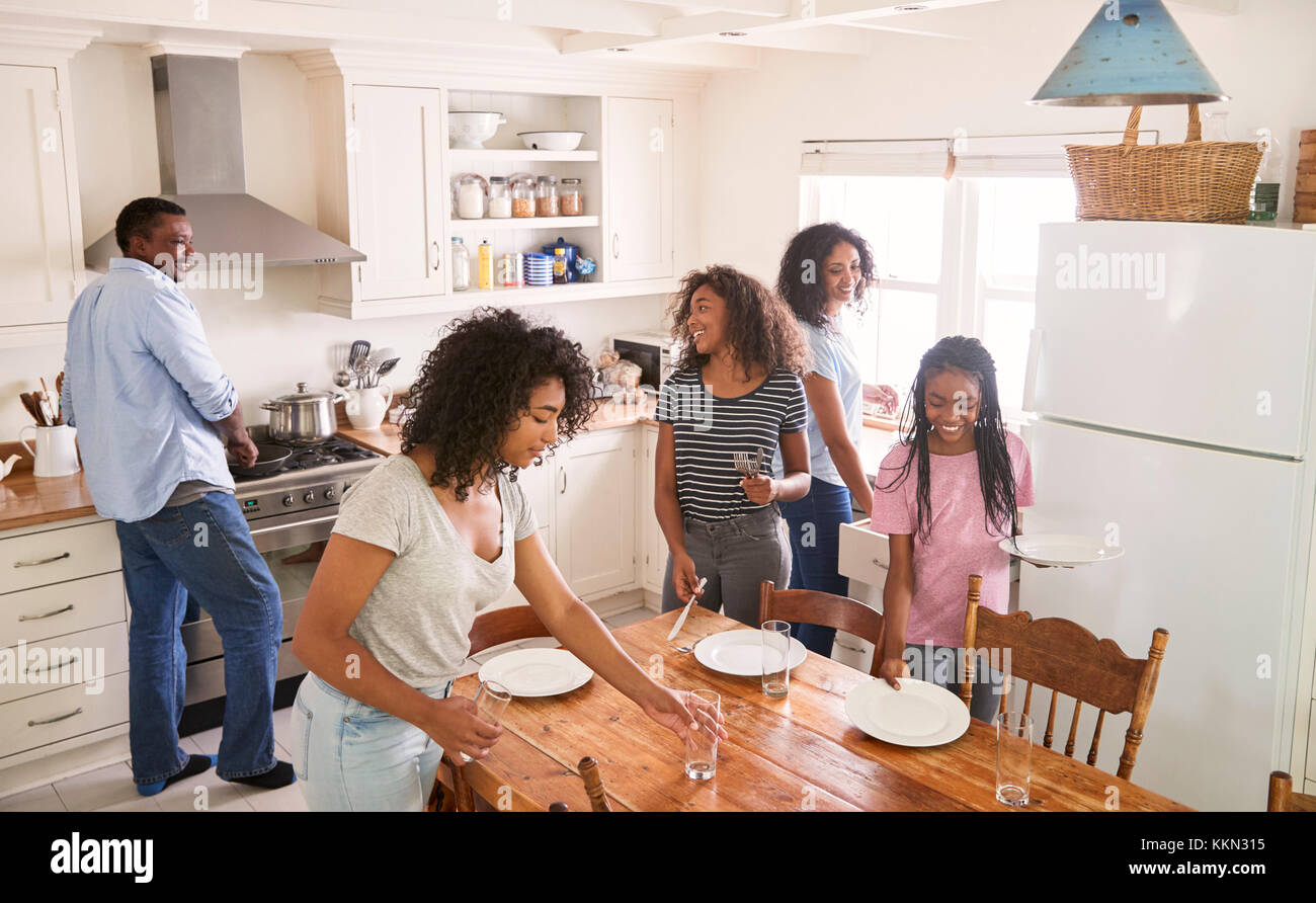 Famille avec filles adolescentes portant la Table de repas en cuisine Banque D'Images