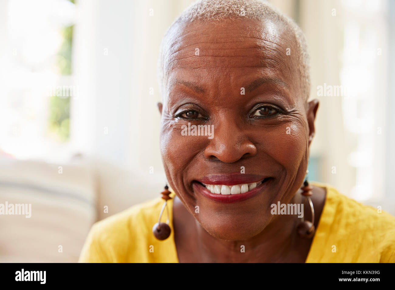 Portrait Of Smiling Senior Woman Sitting on Sofa At Home Banque D'Images