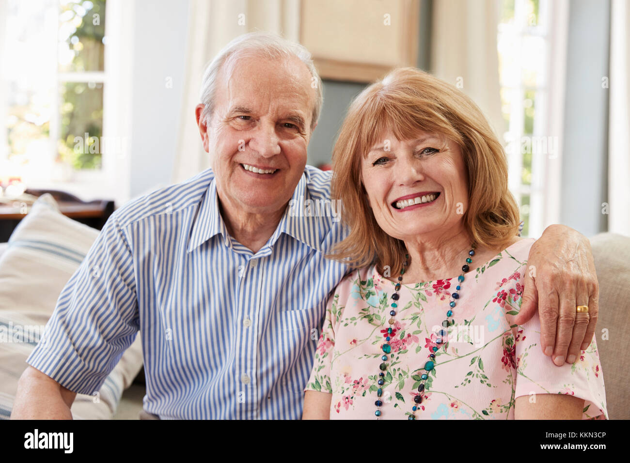 Portrait Of Smiling Senior Couple Sitting on Sofa At Home Banque D'Images