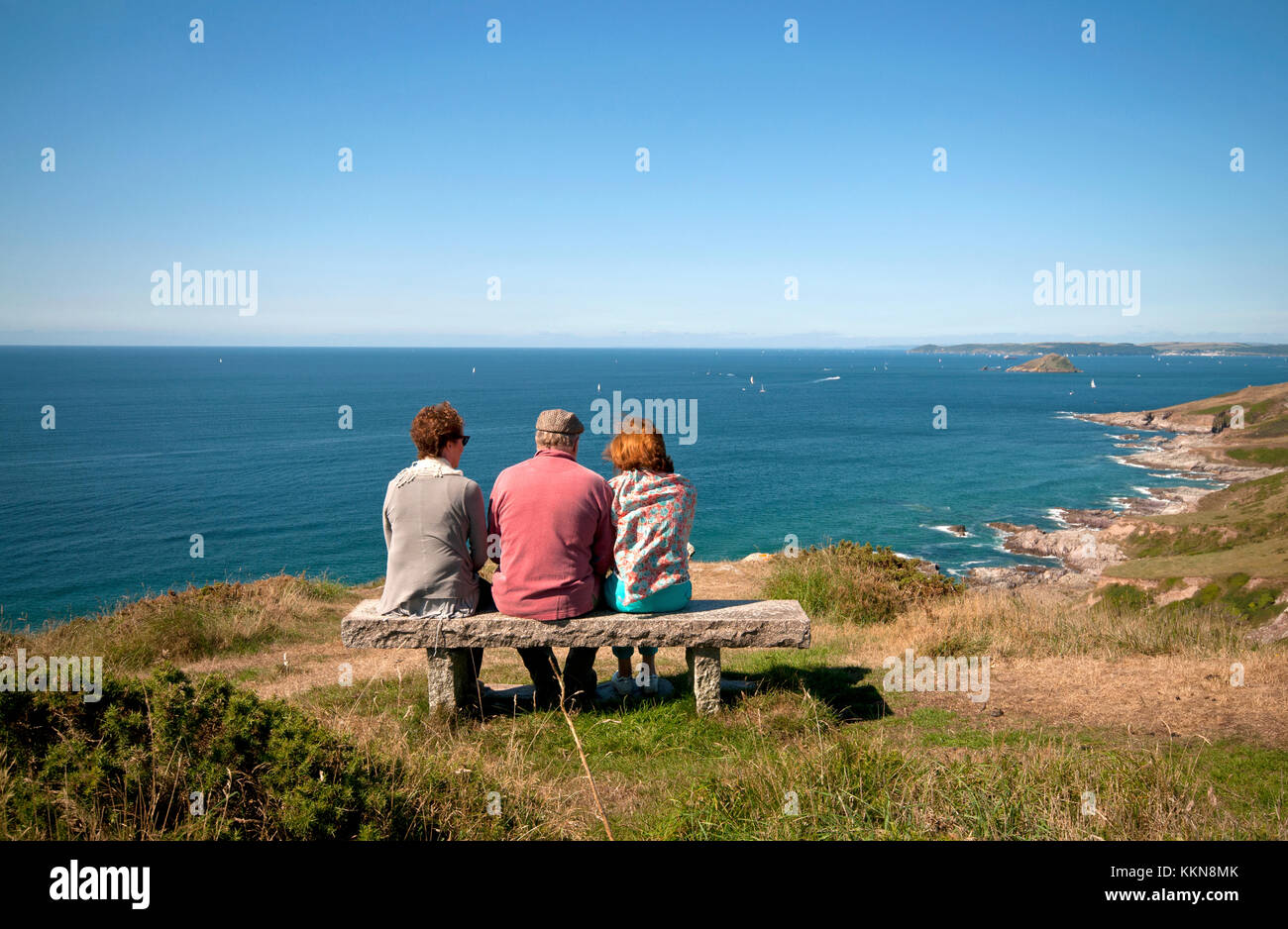 Trois adultes assis sur un banc en admirant la vue sur la côte sud du Devon Banque D'Images