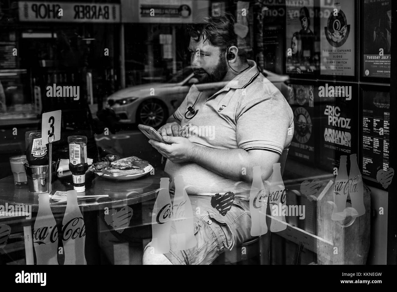 Homme mange le petit-déjeuner pendant l'utilisation de téléphone dans le centre-ville de Manchester, Angleterre, RU Banque D'Images