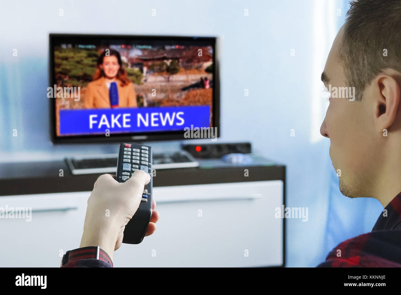 Fake news canular de propagande télévision politique sociale internet. Jeune homme regardant le faux reportage sur la tv à la maison. L'agitation et de la propagande dans le moderne Banque D'Images