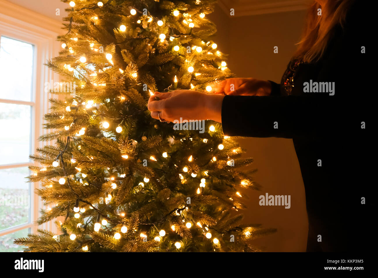 Femme vêtue de noir avec christmas lights par baie vitrée Banque D'Images