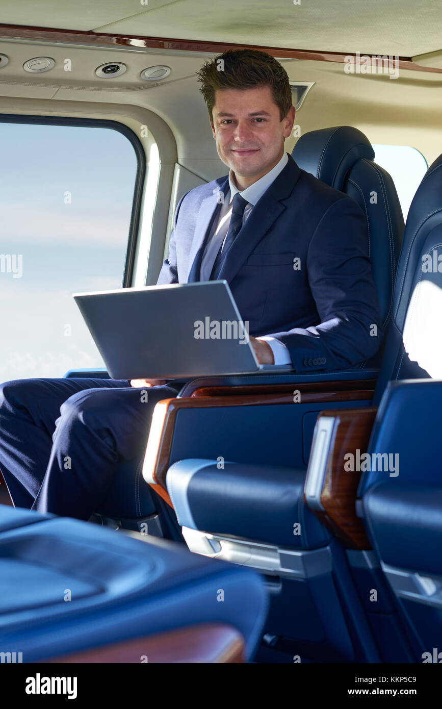 Portrait of businessman working on laptop in cabine de l'hélicoptère pendant le vol. Banque D'Images
