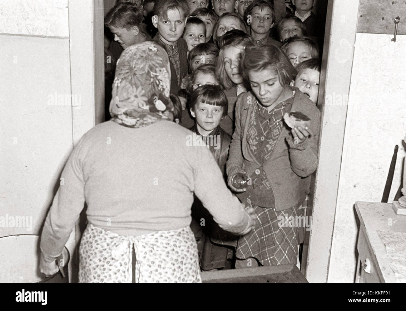 La photographie 'Otroci PRI delitvi malice v Mariboru 1956' montre des enfants partageant un repas à Maribor, Slovénie, dans les années 1950 L'image capture la vie quotidienne des enfants d'après-guerre en Yougoslavie socialiste, reflétant l'atmosphère culturelle et sociale de l'époque. Banque D'Images