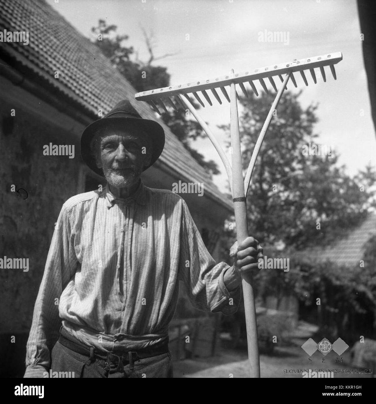 Janez Intihar, un homme de 85 ans originaire de Javorje, Slovénie, est représenté en 1960 avec des râteaux fabriqués à la main qu'il a lui-même fabriqués. La photographie illustre l'artisanat et le dévouement de la vie rurale en Slovénie à cette époque. Banque D'Images