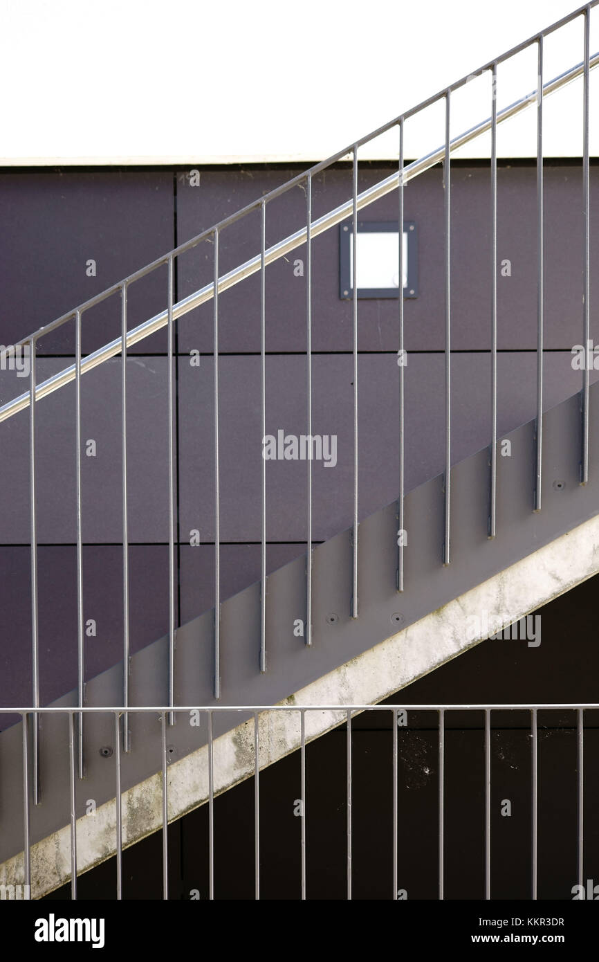 Détail des escaliers modernes avec une rambarde en acier inoxydable et une applique murale. Banque D'Images