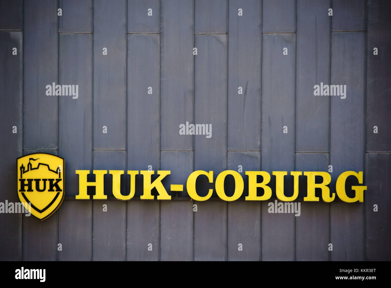 Le signe et le logo jaune de la compagnie d'assurance HUK Coburg sur une façade en étain d'un immeuble de bureaux. Banque D'Images