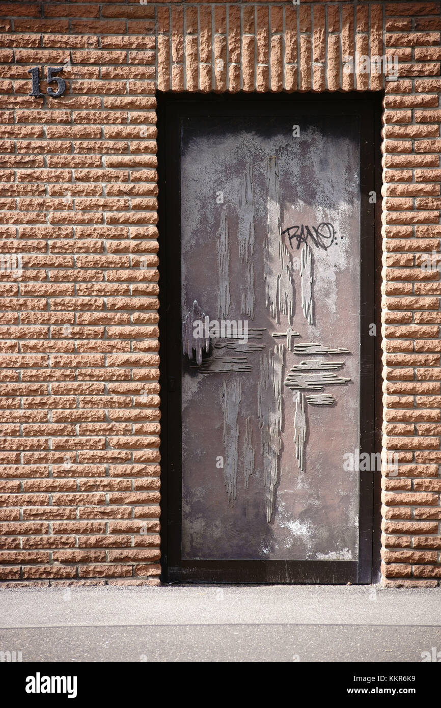 Une porte métallique avec un motif de surface tranchant dans une façade en clinker de pierres brutes. Banque D'Images