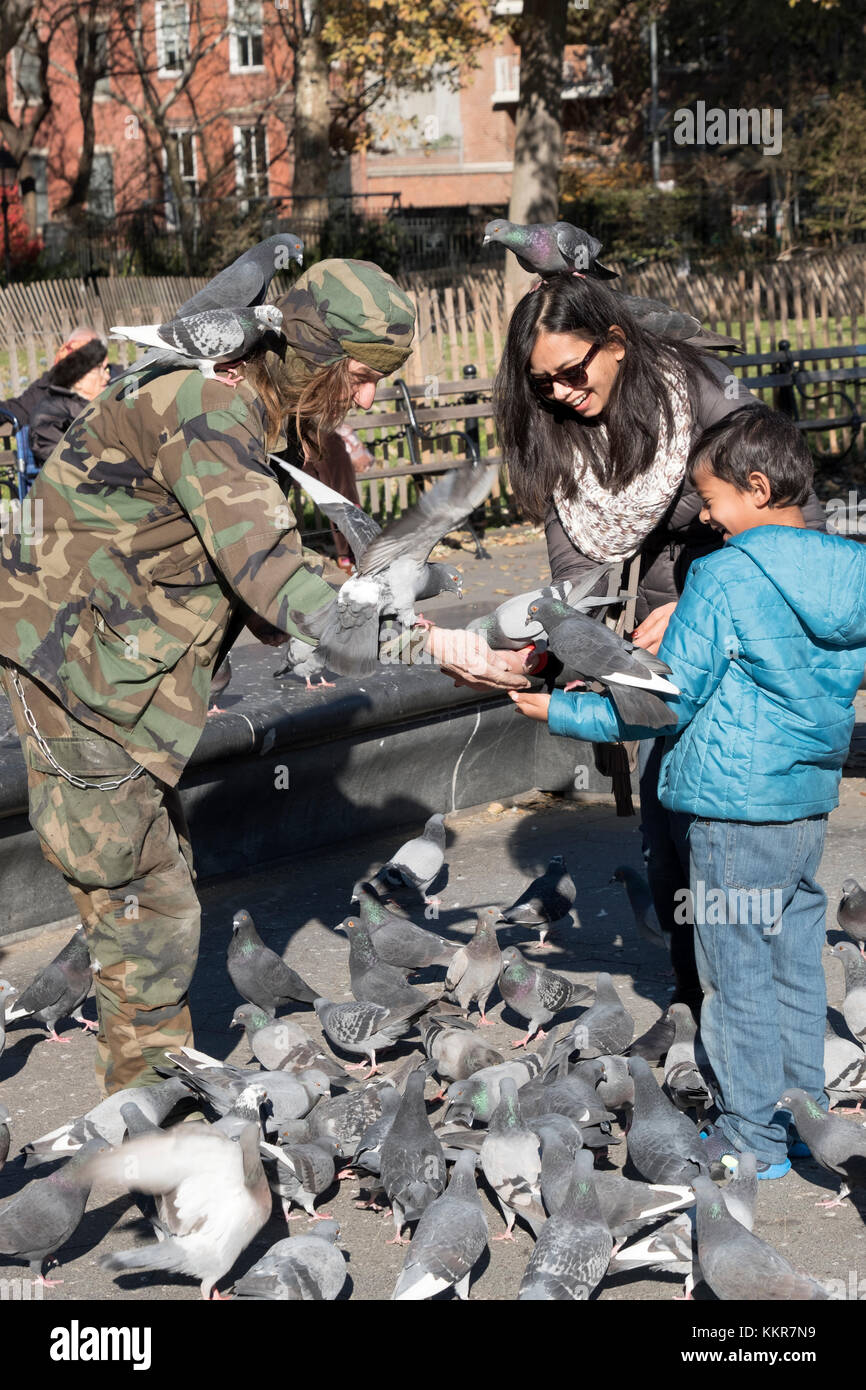 Larry, un des hommes de pigeon Washington Square Park, reçoit une offre d'enfant et sa maman puisqu'elles se nourrissent les pigeons et de recueillir une foule d'oiseaux. Banque D'Images