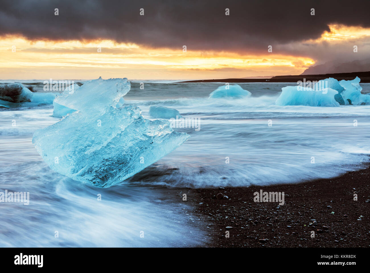 L'Est de l'Islande, Jokulsarlon, l'Europe. Blocs de glace sur la plage noire dans le lagon du Glacier Jökulsárlón lors d'un coucher du soleil Banque D'Images