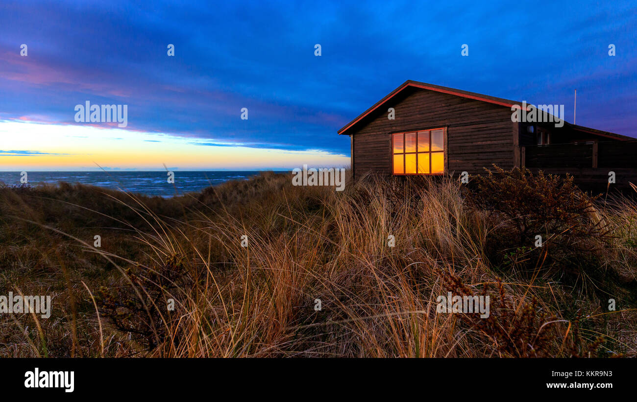 Maison dans les dunes au coucher du soleil sur une plage près de Hirtshals. Banque D'Images