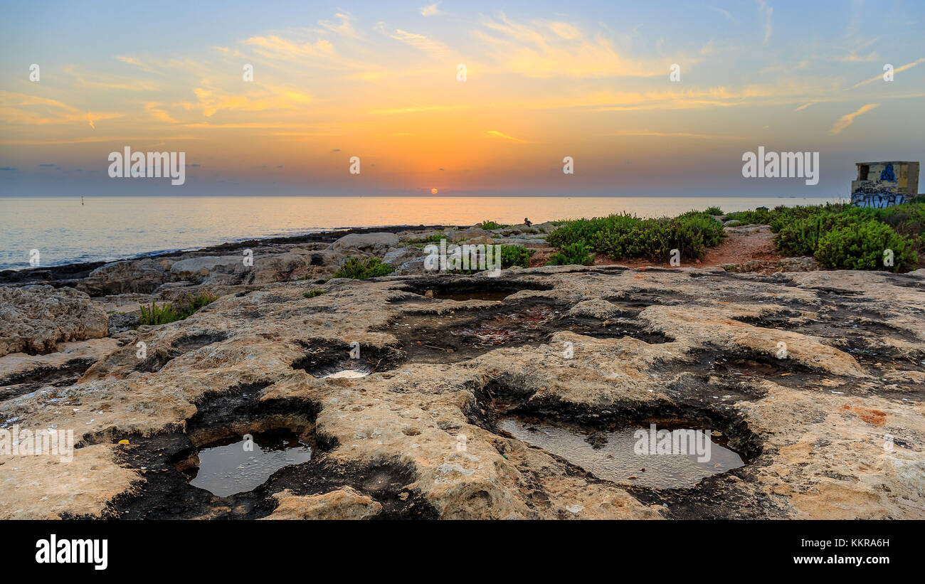Coucher de soleil sur la plage rocheuse de Paceville, à Malte Banque D'Images