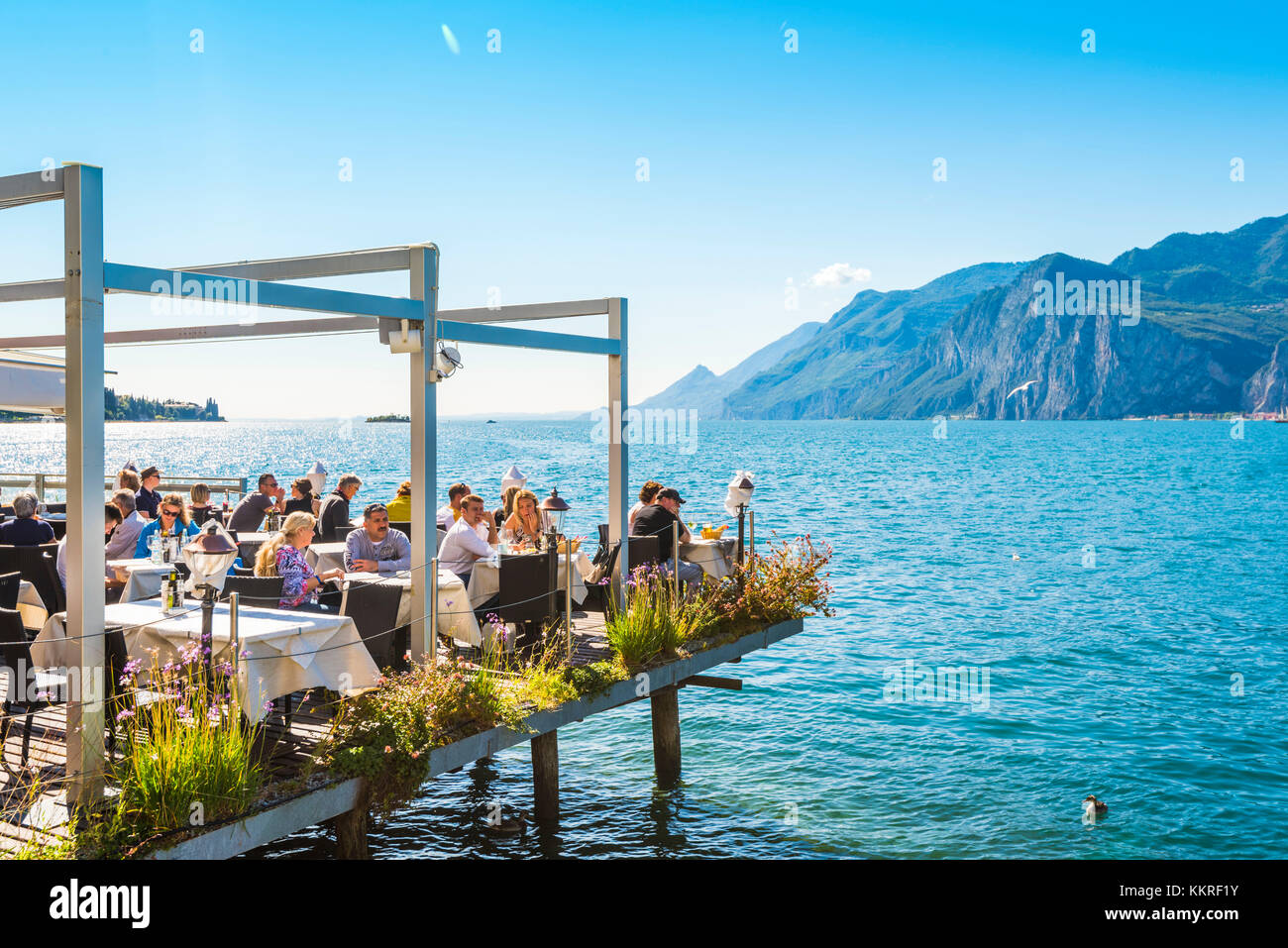 Malcesine, lac de Garde, province de Vérone, Vénétie, Italie. Les touristes mangent dans un restaurant sur l'eau. Banque D'Images