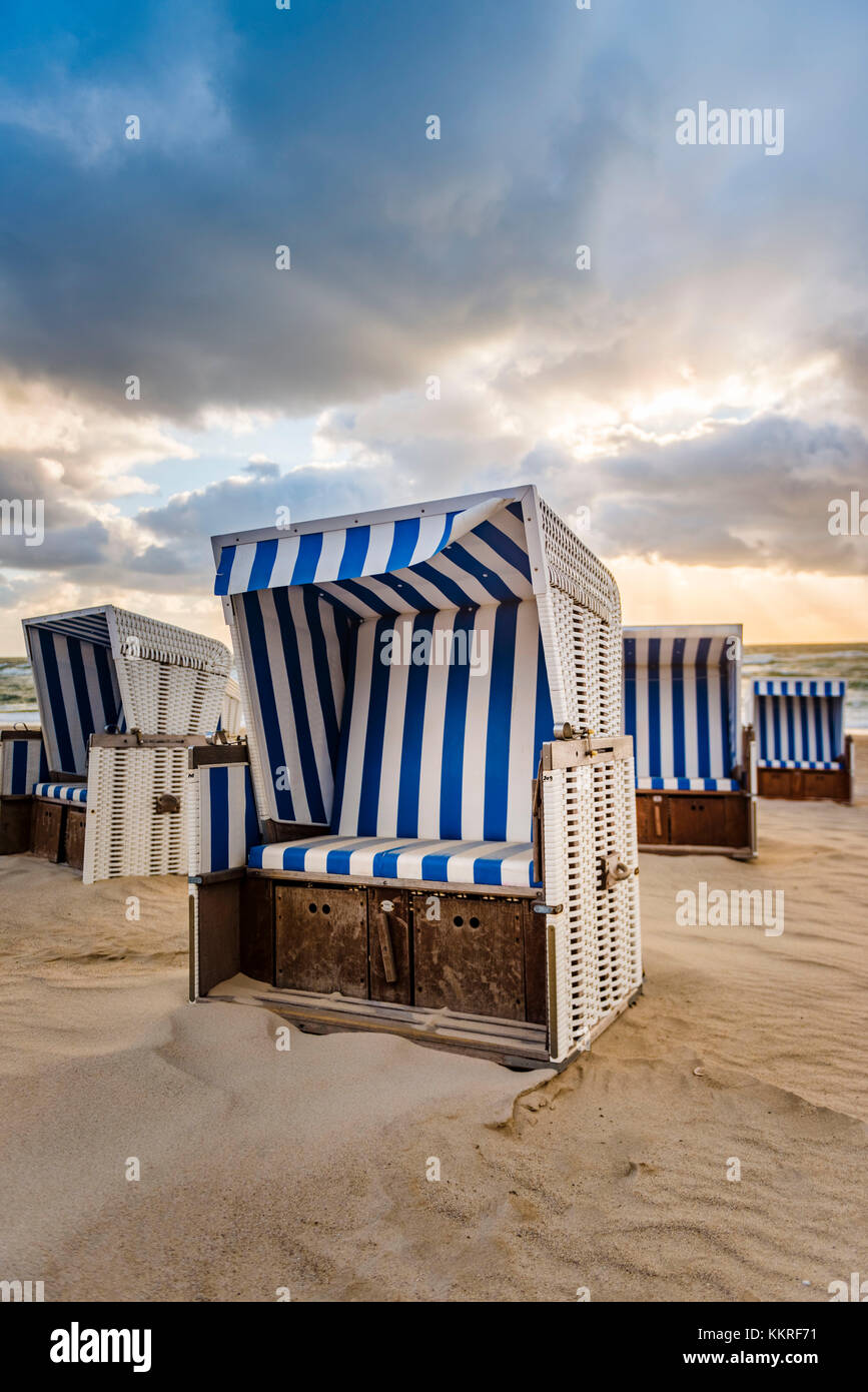 Kampen, l'île de Sylt, Frise du Nord, Schleswig-Holstein, Allemagne. Strandkorbs sur la plage au coucher du soleil. Banque D'Images