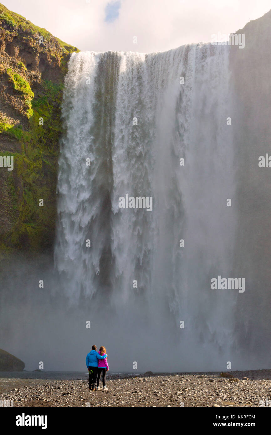 Un couple regardant cascade skogafoss, skogar, sudurland, Islande Banque D'Images