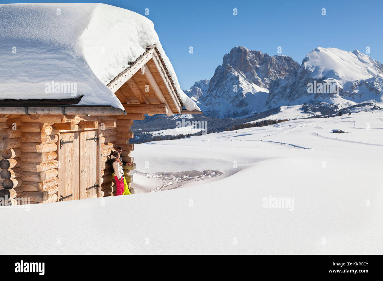 Un couple de skieurs sont de détente sous le soleil sur l''Alpe di Siusi avec le groupe langkofel en arrière-plan, la province de Bolzano, le Tyrol du sud, Trentin-Haut-Adige, Italie Banque D'Images
