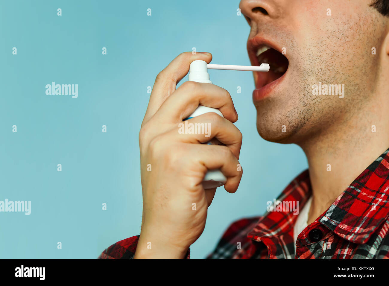 Jeune homme malade à l'aide de pulvérisation de la gorge sur un fond de couleur. l'haleine fraîche. Vaporiser pour éliminer la mauvaise haleine. mint pulvérisée. Banque D'Images