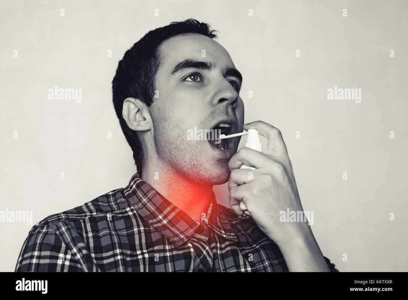 Jeune homme guérit sa gorge. l'homme éclabousse dans la gorge pulvérisée. L'inflammation dans la gorge. le traitement du rhume. traitement des ulcères sur le grip. Banque D'Images