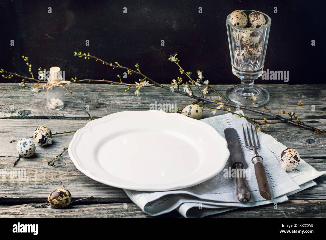 Table de pâques avec l'argenterie vintage, plaque blanche, gris serviette textile, œufs de caille et blossom branch sur la vieille table en bois Banque D'Images