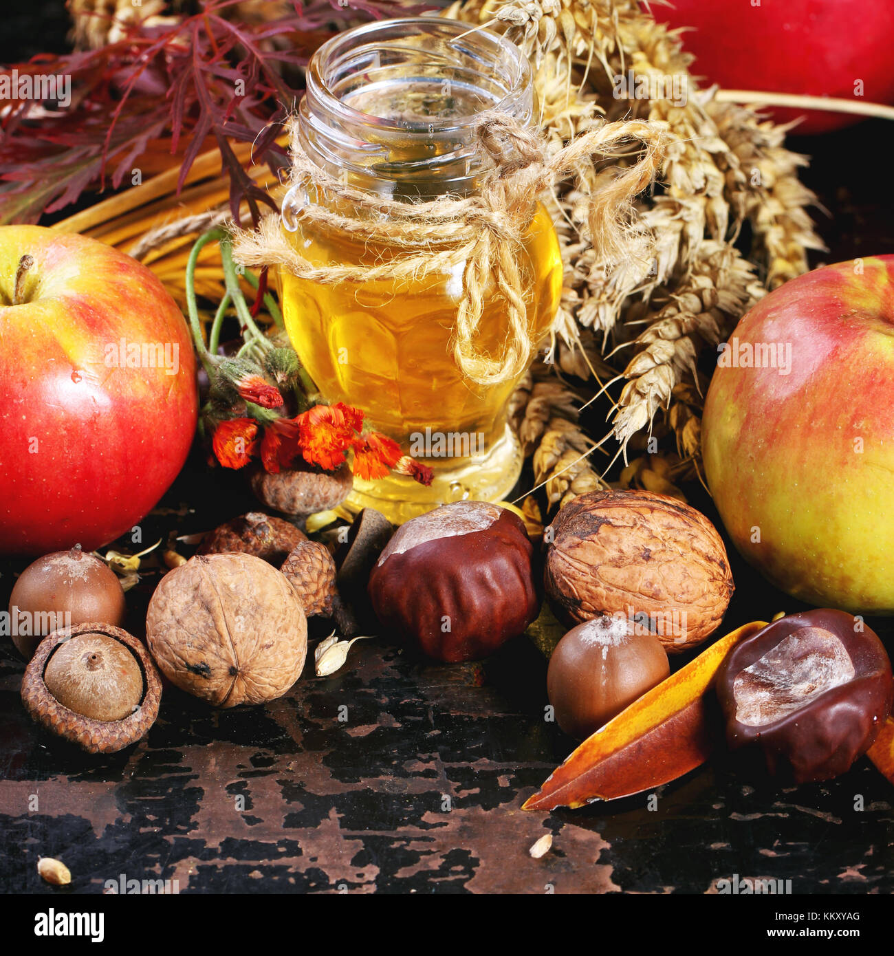 Pot de miel en verre avec des pommes, des épis de blé, les châtaignes et les noix de table en bois noir. le carré de droit avec selective focus Banque D'Images