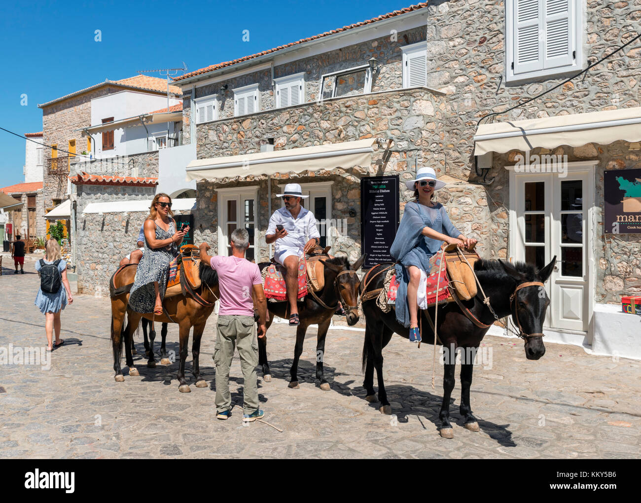 Les touristes de prendre une promenade avec un âne à travers les rues de la ville d''Hydra, Hydra, îles saroniques, Grèce Banque D'Images