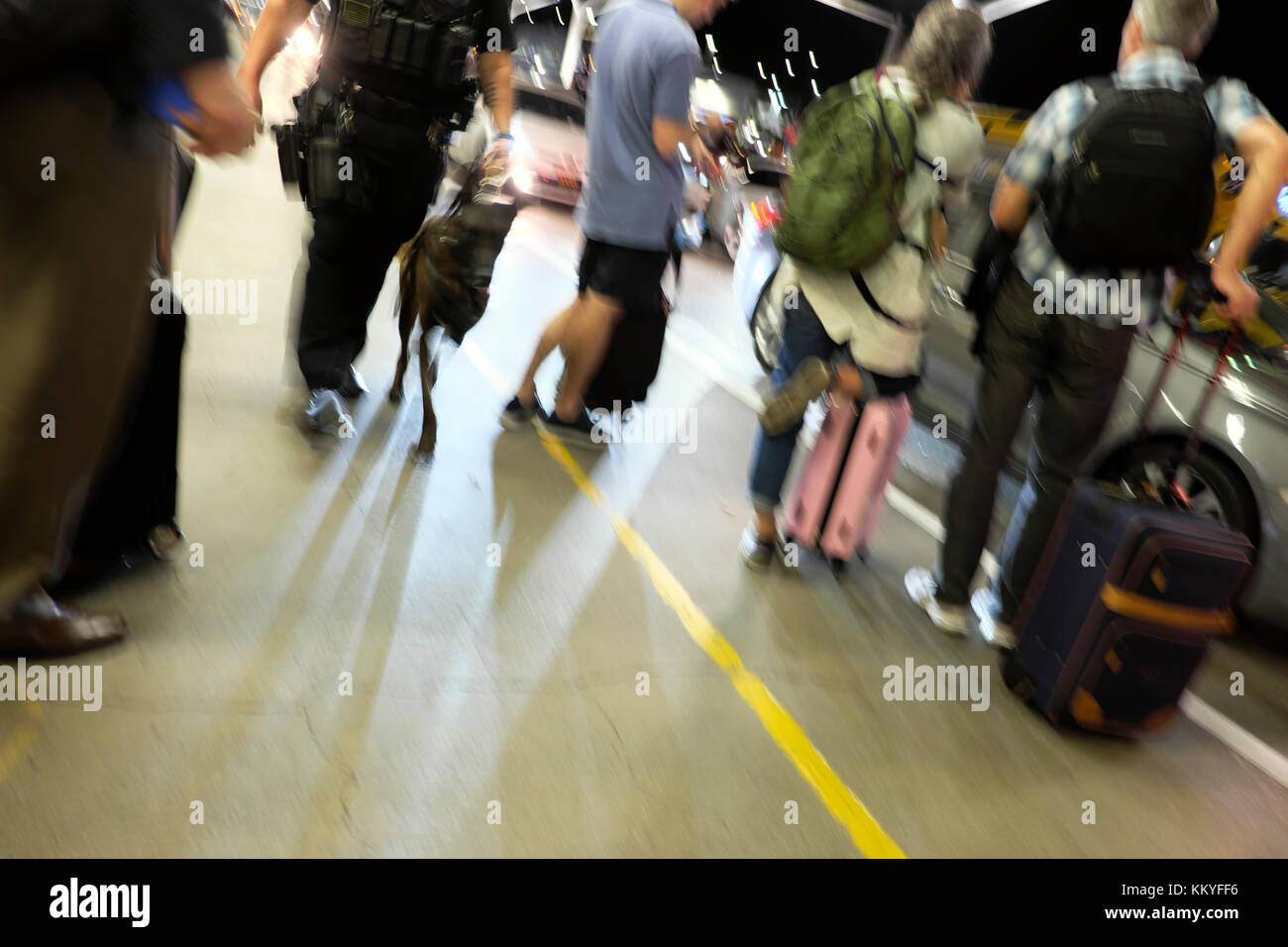 Image floue du policier walking dog passé les personnes en attente de collecte par un Uber taxi à l'aéroport LAX Los Angeles California USA KATHY DEWITT Banque D'Images