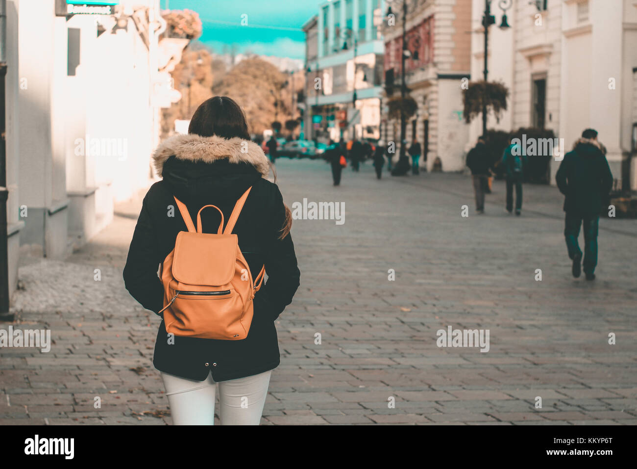 Jeune fille à la veste et sac à dos, marchant sur un trottoir du centre-ville road shopping pour Noël teal et orange Banque D'Images
