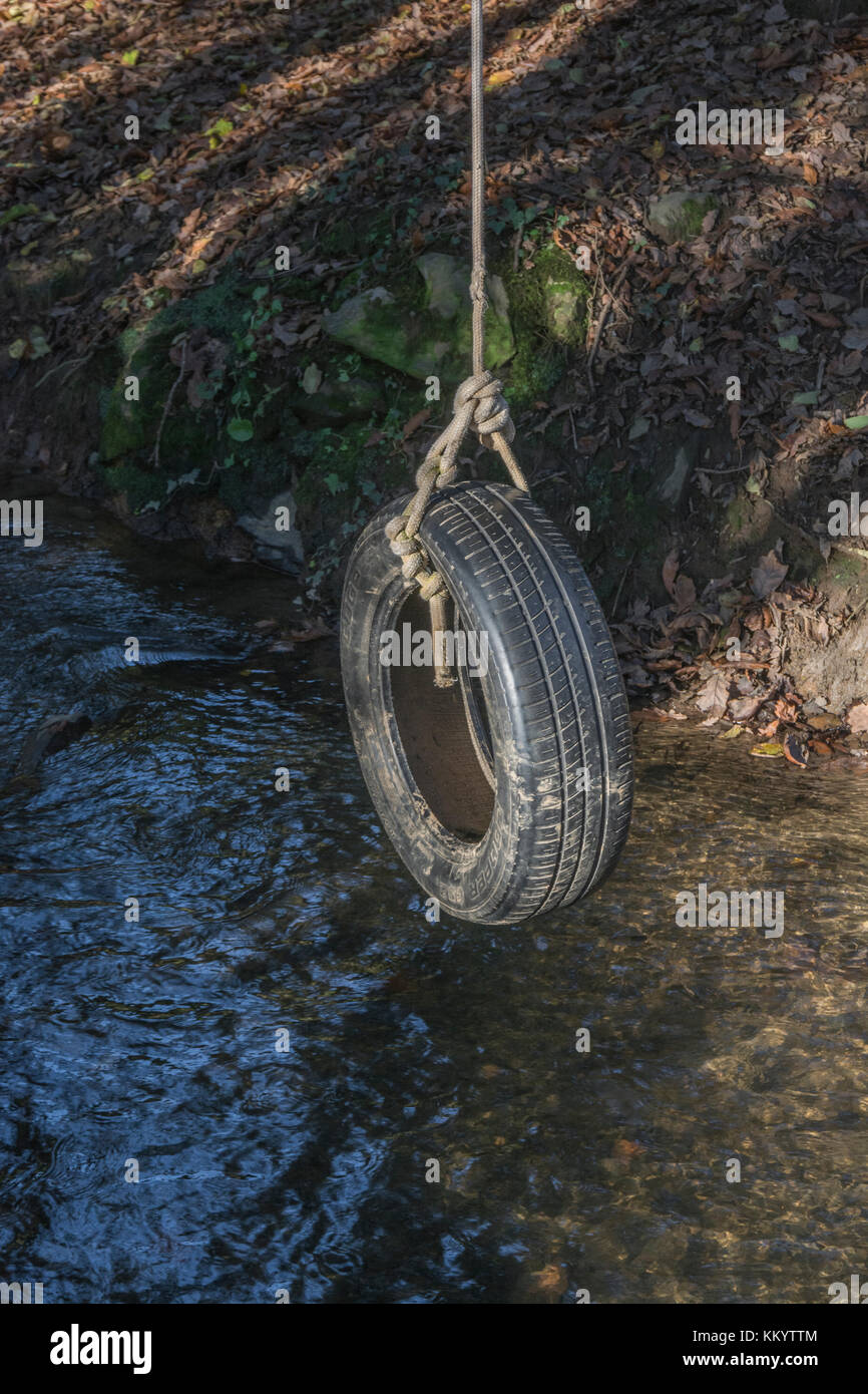 Balancement de pneu de voiture ancienne / balancement de pneu au repos sur un ruisseau de pays - rappelle l'un de l'amusement d'enfance et aussi la métaphore pour les balançoires de pendule. Banque D'Images